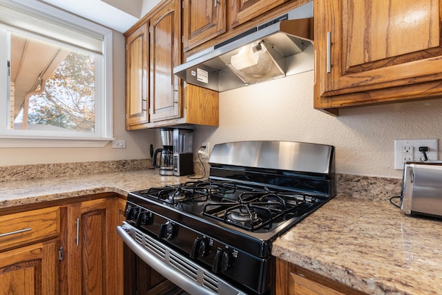 kitchen featuring ventilation hood, light stone countertops, and stainless steel range with gas cooktop