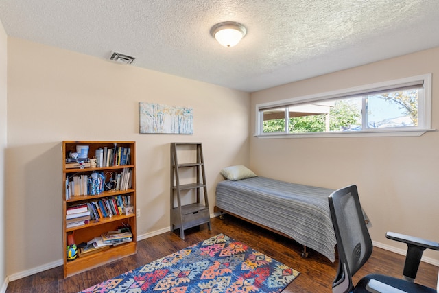 bedroom featuring a textured ceiling and dark wood-type flooring