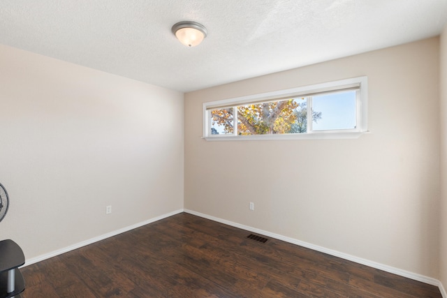 unfurnished room featuring a textured ceiling and dark wood-type flooring