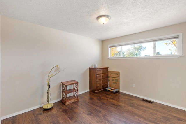 interior space with a textured ceiling and dark hardwood / wood-style flooring