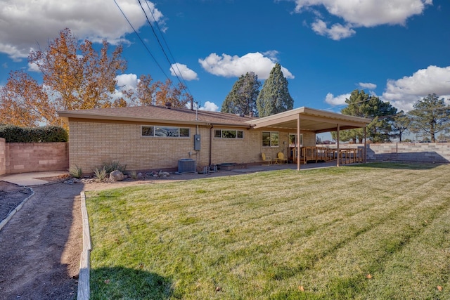 rear view of property featuring central AC unit, a patio area, and a lawn