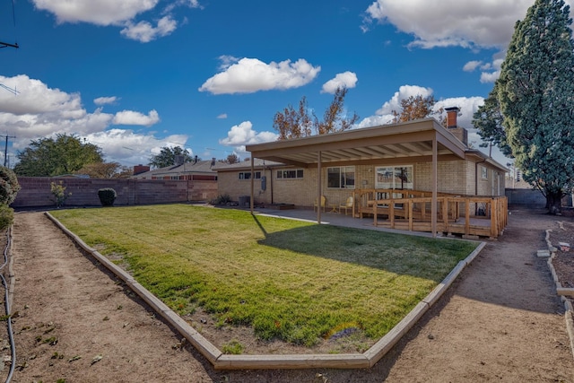 rear view of house featuring a lawn, a wooden deck, and a patio