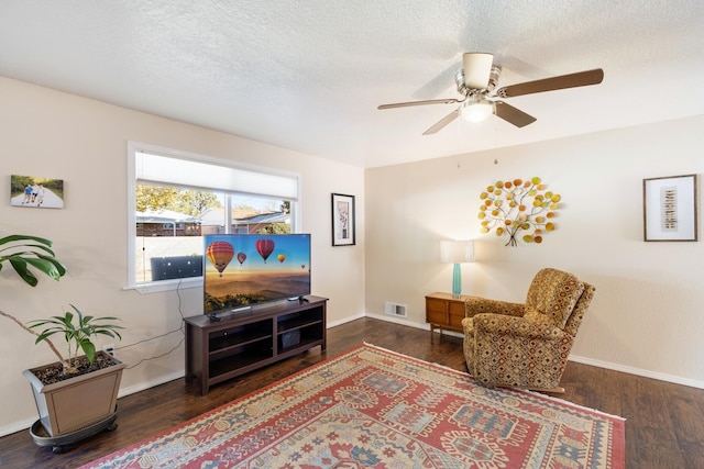 living area featuring a textured ceiling, ceiling fan, and dark wood-type flooring