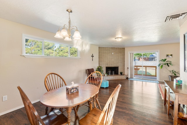 dining area featuring dark hardwood / wood-style flooring, a fireplace, a textured ceiling, and a notable chandelier