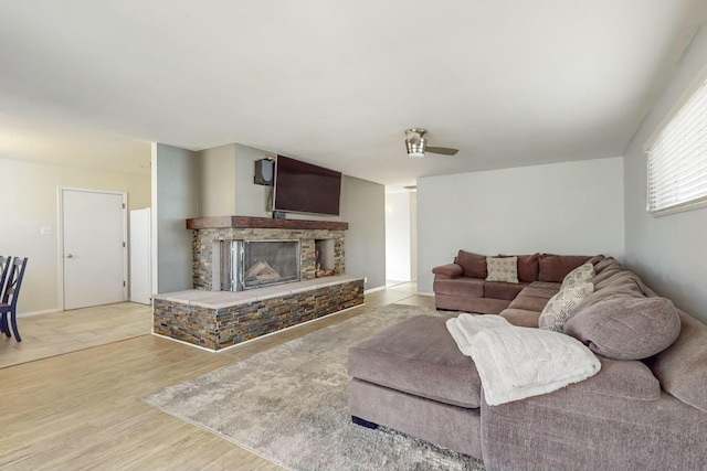 living room with ceiling fan, light hardwood / wood-style floors, and a fireplace