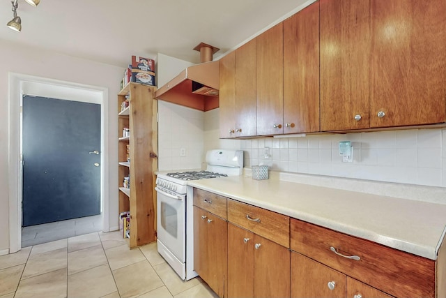 kitchen with decorative backsplash, light tile patterned floors, and white gas range oven