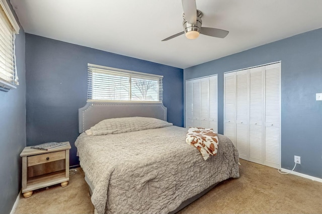 carpeted bedroom with ceiling fan and multiple closets