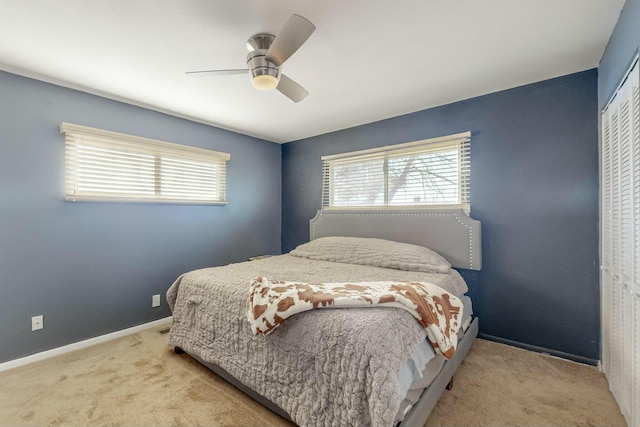 bedroom with light carpet, a closet, multiple windows, and ceiling fan