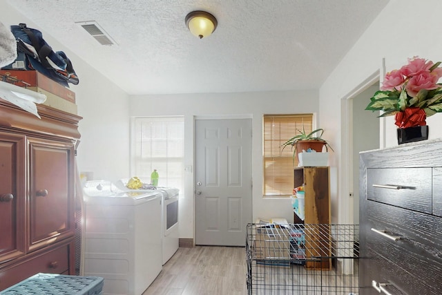 washroom with washer and dryer, a textured ceiling, and light wood-type flooring