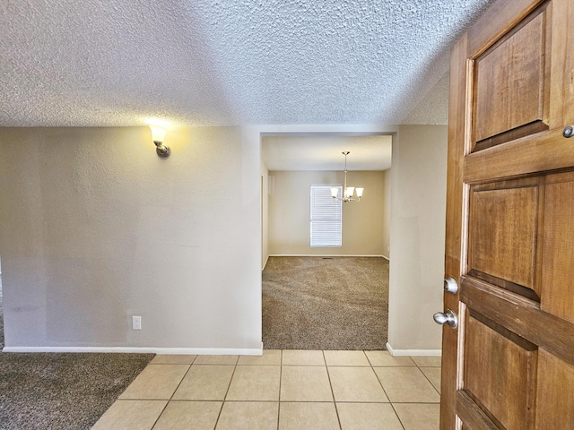 carpeted foyer entrance with a textured ceiling and a chandelier