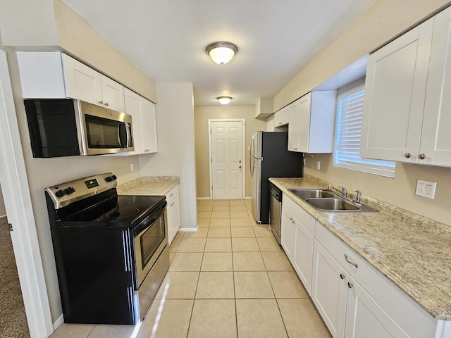 kitchen with white cabinetry, sink, light stone countertops, light tile patterned flooring, and appliances with stainless steel finishes