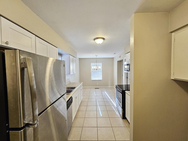 kitchen featuring hanging light fixtures, a notable chandelier, light tile patterned flooring, white cabinetry, and stainless steel appliances