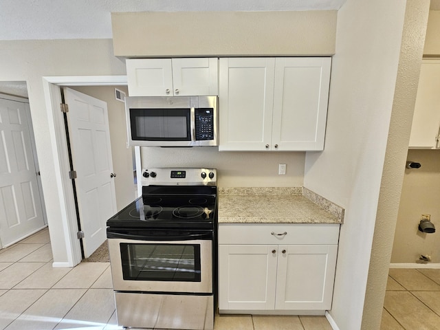 kitchen featuring white cabinets, light tile patterned floors, and appliances with stainless steel finishes