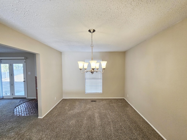 carpeted spare room with a textured ceiling and a notable chandelier