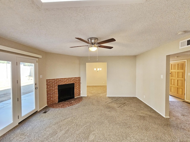 unfurnished living room with carpet, a textured ceiling, ceiling fan with notable chandelier, and a brick fireplace