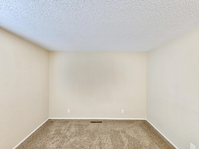 spare room featuring carpet and a textured ceiling