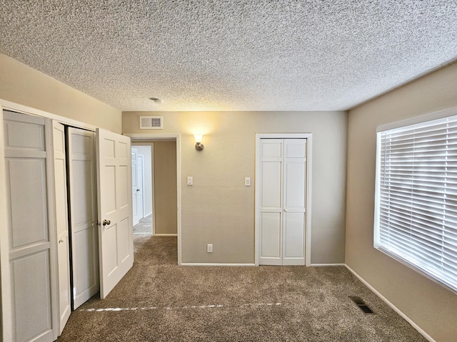 unfurnished bedroom featuring a textured ceiling and dark colored carpet