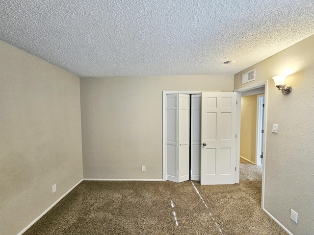 unfurnished bedroom featuring dark colored carpet, a textured ceiling, and a closet