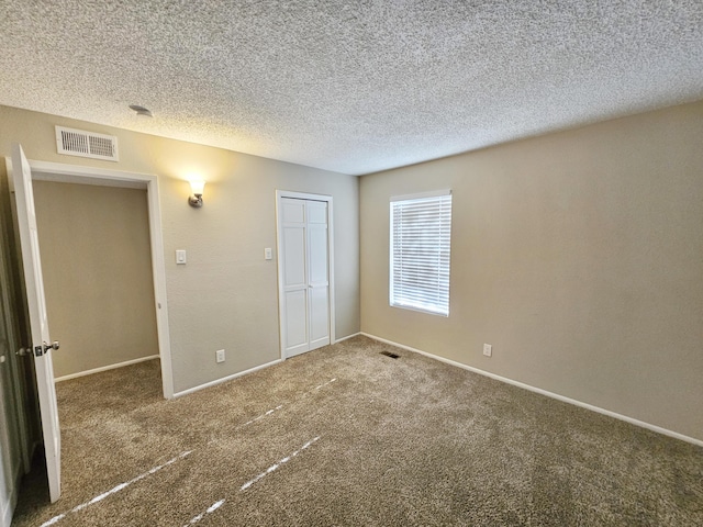 unfurnished bedroom featuring a textured ceiling, carpet floors, and a closet