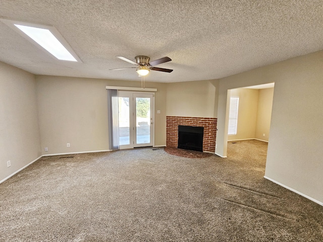 unfurnished living room featuring carpet, a textured ceiling, a brick fireplace, and ceiling fan