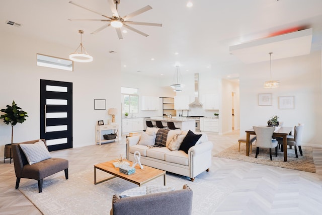 living room featuring ceiling fan, a high ceiling, and light parquet floors