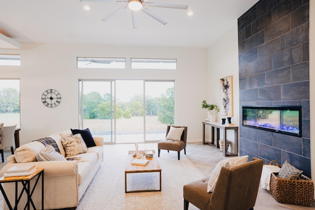 living room with a tiled fireplace, ceiling fan, and light parquet flooring