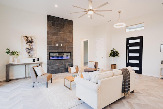 living room with a tile fireplace, a towering ceiling, light parquet flooring, and ceiling fan