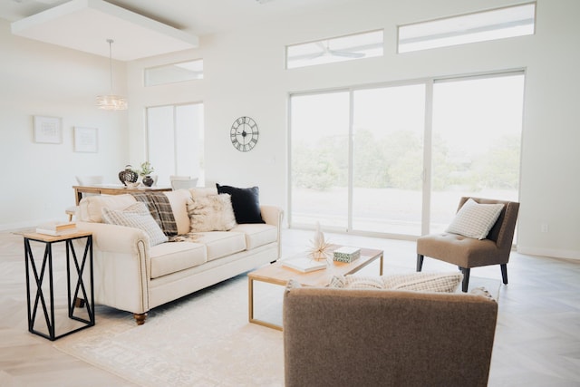 living room with a towering ceiling, ceiling fan with notable chandelier, and light parquet floors