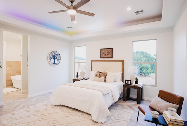 bedroom with ceiling fan, light parquet floors, multiple windows, and a tray ceiling