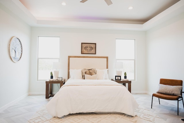 bedroom with light parquet flooring, a raised ceiling, and ceiling fan