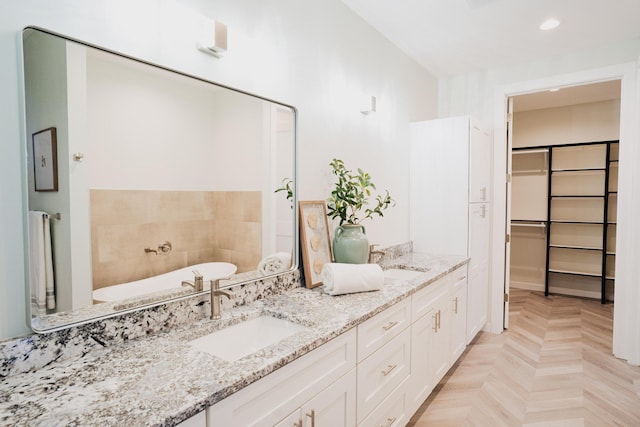 bathroom with a bathing tub, vanity, and parquet flooring