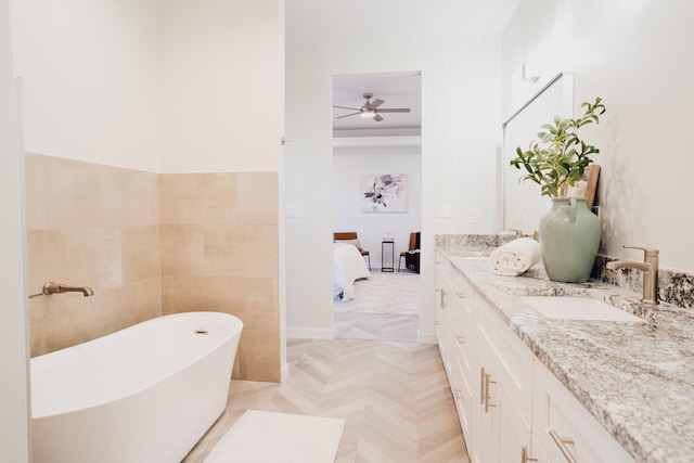 bathroom with parquet flooring, a bath, vanity, and ceiling fan