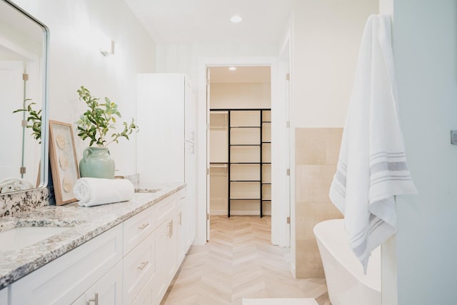 bathroom featuring vanity, parquet flooring, and a tub