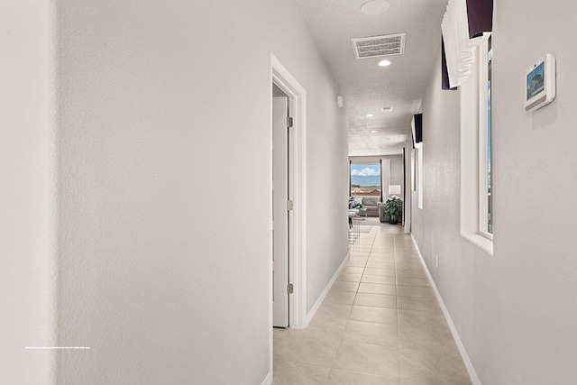 hall with light tile patterned floors and a textured ceiling