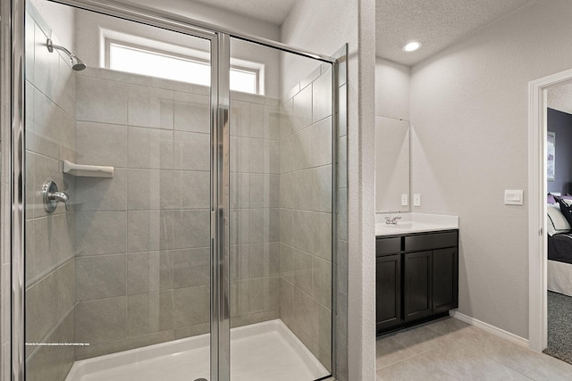 bathroom featuring tile patterned flooring, vanity, a shower with door, and a textured ceiling