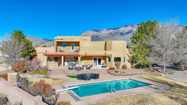 back of house featuring a patio, a mountain view, a balcony, fence, and stucco siding