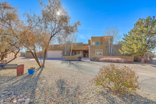 view of front facade with an attached garage, a fenced front yard, a gate, and stucco siding