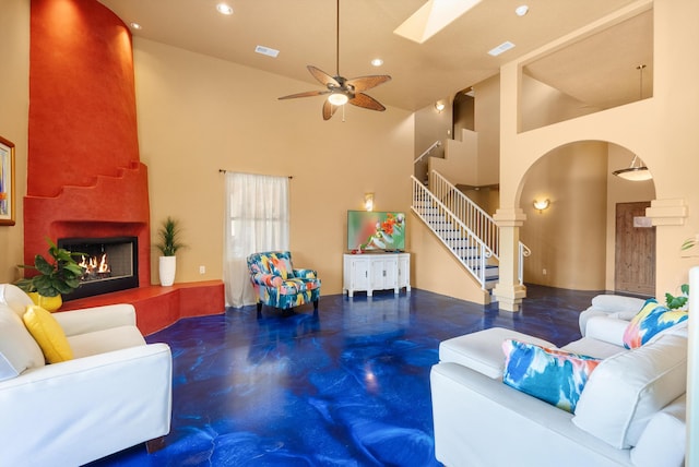 living area with visible vents, a high ceiling, a fireplace, concrete flooring, and stairs