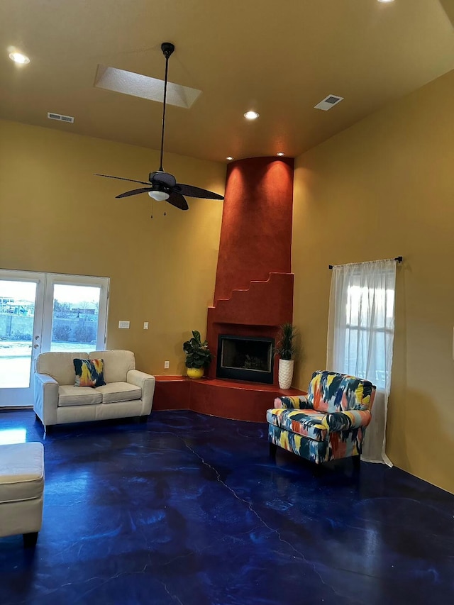 living room with finished concrete flooring, a fireplace, visible vents, and a high ceiling