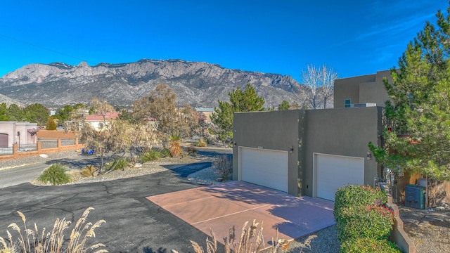 exterior space featuring a garage, a mountain view, driveway, and stucco siding