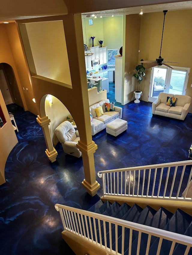 living area featuring a ceiling fan, arched walkways, and stairway