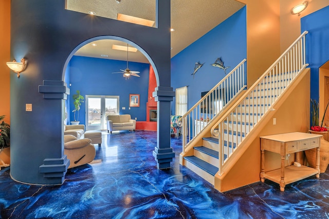 stairway featuring a textured ceiling, a towering ceiling, and ceiling fan