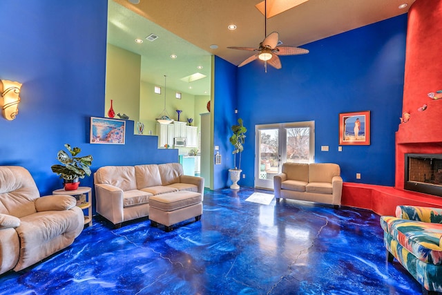 living room with ceiling fan, a towering ceiling, and a textured ceiling