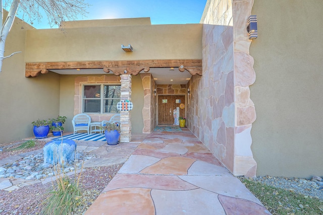 view of exterior entry with a porch and stucco siding