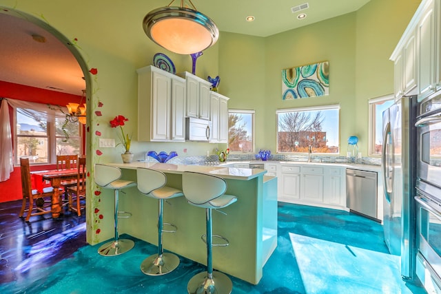 kitchen featuring visible vents, arched walkways, white cabinets, appliances with stainless steel finishes, and a peninsula