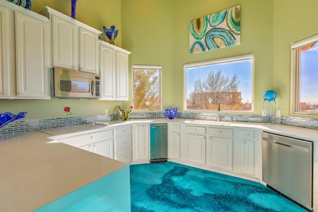 kitchen featuring white cabinets, a sink, stainless steel appliances, and light countertops