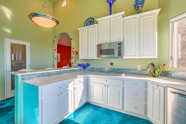 kitchen featuring stainless steel appliances, a peninsula, light countertops, and white cabinets