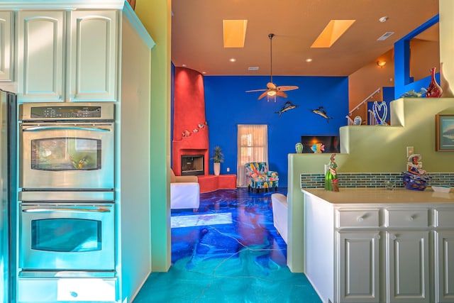 kitchen featuring white cabinets, stainless steel double oven, a skylight, and tasteful backsplash