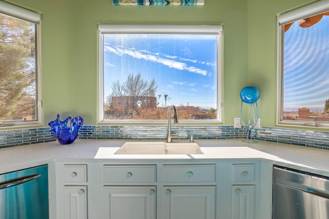 kitchen featuring light countertops, stainless steel dishwasher, a sink, and tasteful backsplash