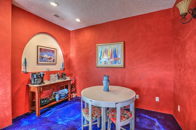 dining area featuring a textured ceiling and dark colored carpet